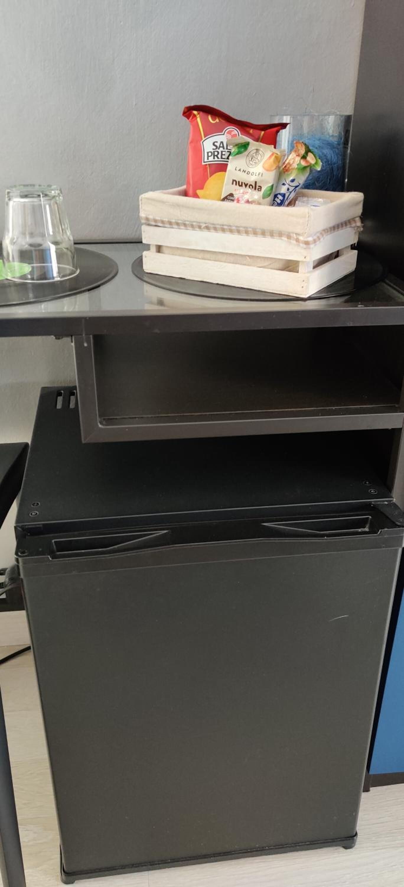 Un refrigerador negro con una pila de cajas blancas y una bolsa de aperitivos encima.
