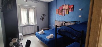 Un dormitorio con dos camas, una ventana con cortinas, un radiador y una pared decorada con obras de arte.