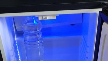 A refrigerator with a water bottle inside, illuminated by blue light.