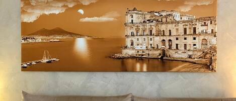 A wall-mounted artwork of a coastal town with a prominent building and a crescent moon.