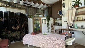 Une pièce comprenant un lit, un bureau, une chaise, un luminaire suspendu et une plante.