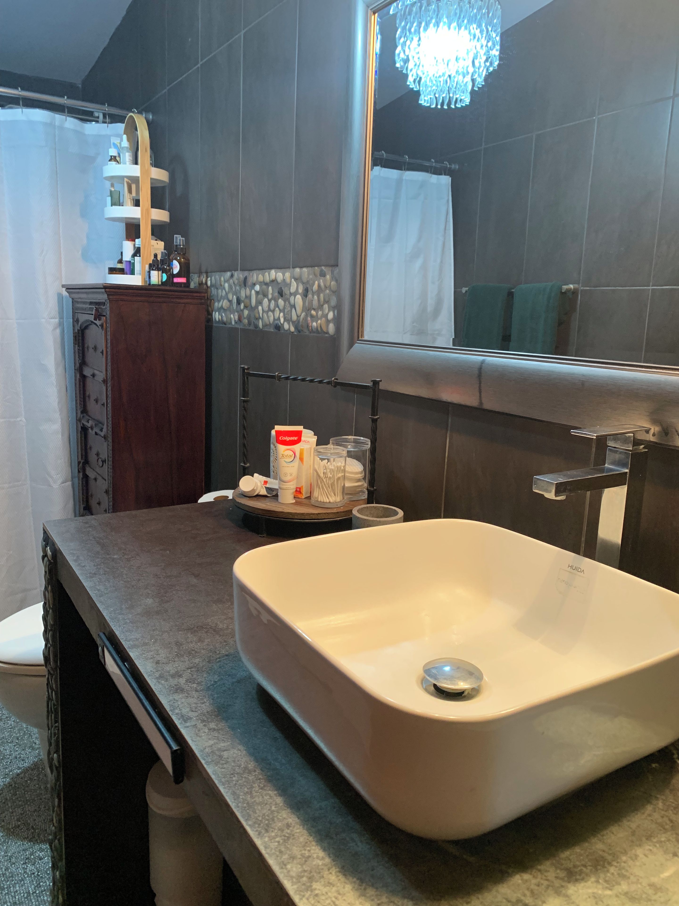 Un baño con lavamanos blanco, un espejo y artículos de aseo en la encimera.
