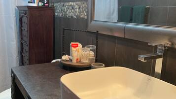 A bathroom with a white sink, a mirror, and toiletries on the counter.