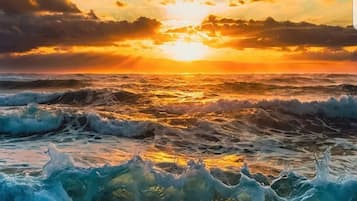 Un atardecer sobre el océano con olas rompiendo en la orilla.