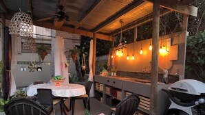 Un patio al aire libre con una mesa, sillas, una parrilla y luces colgantes.