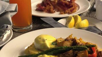 Ein Frühstückstisch mit Eiern Benedict, Speck und einem Glas Orangensaft.