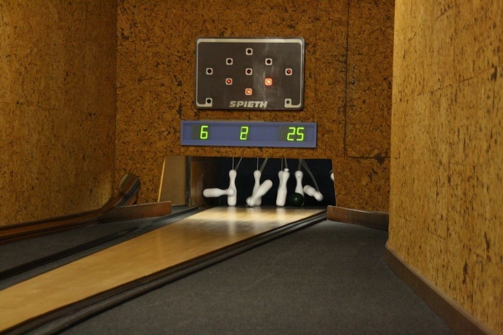 A bowling alley with a scoreboard displaying scores.