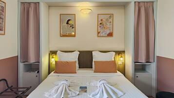 Una habitación de hotel con una cama, dos mesitas de noche, una silla y dos lámparas de pared.