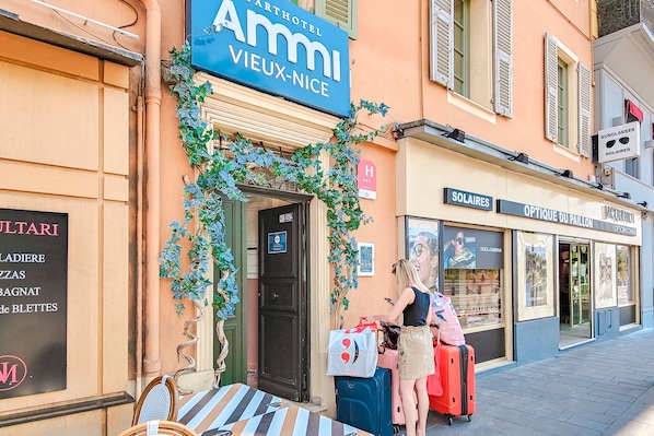 Entrada de un hotel con un letrero que dice "Ammi Vieux-Nice" y una tienda cercana llamada "Soleares".