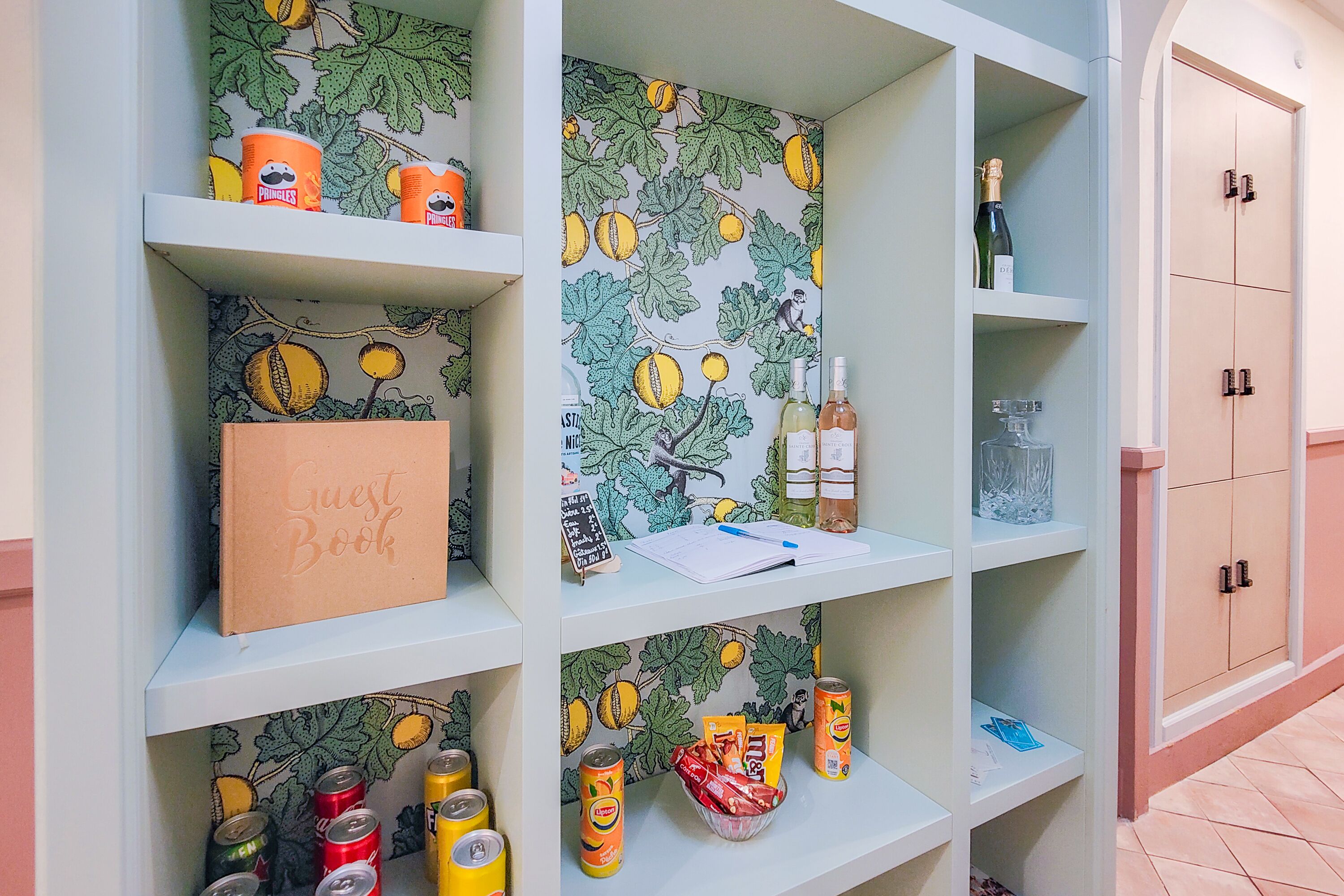 Een kamer met een boekenplank vol verschillende spullen, zoals een gastenboek, blikken en flessen.