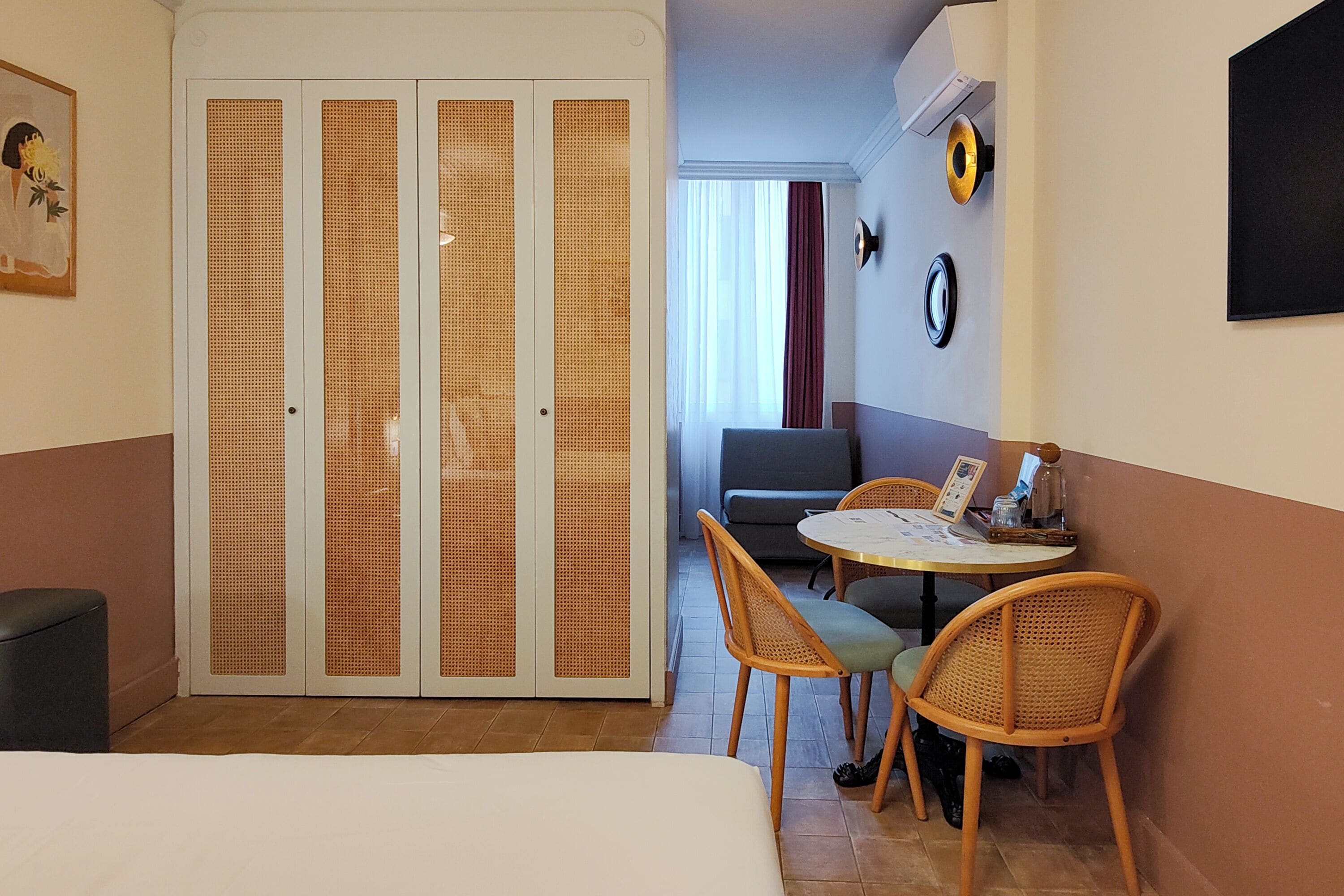 Een kamer met een bed, een eettafel met stoelen, een bank en een aan de muur bevestigde televisie.