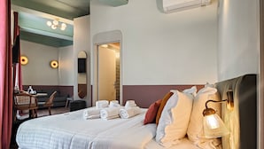 A hotel room with a bed, a desk, a chair, a mirror, and a wall-mounted air conditioner. - Hotel Aparthotel AMMI Vieux Nice (Nice)