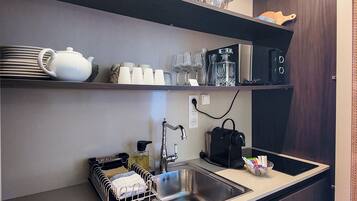Een moderne keuken met een roestvrijstalen spoelbak, een waterkoker en divers servies op planken.