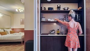 A compact hotel room with a kitchenette, a bed with pillows, and a bedside table. - Hotel Aparthotel AMMI Vieux Nice (Nice)