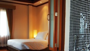 A hotel room with a large bathtub, a bed with white linens, and a view of the room's interior. - The Chalet Phuket Resort (Wichit)