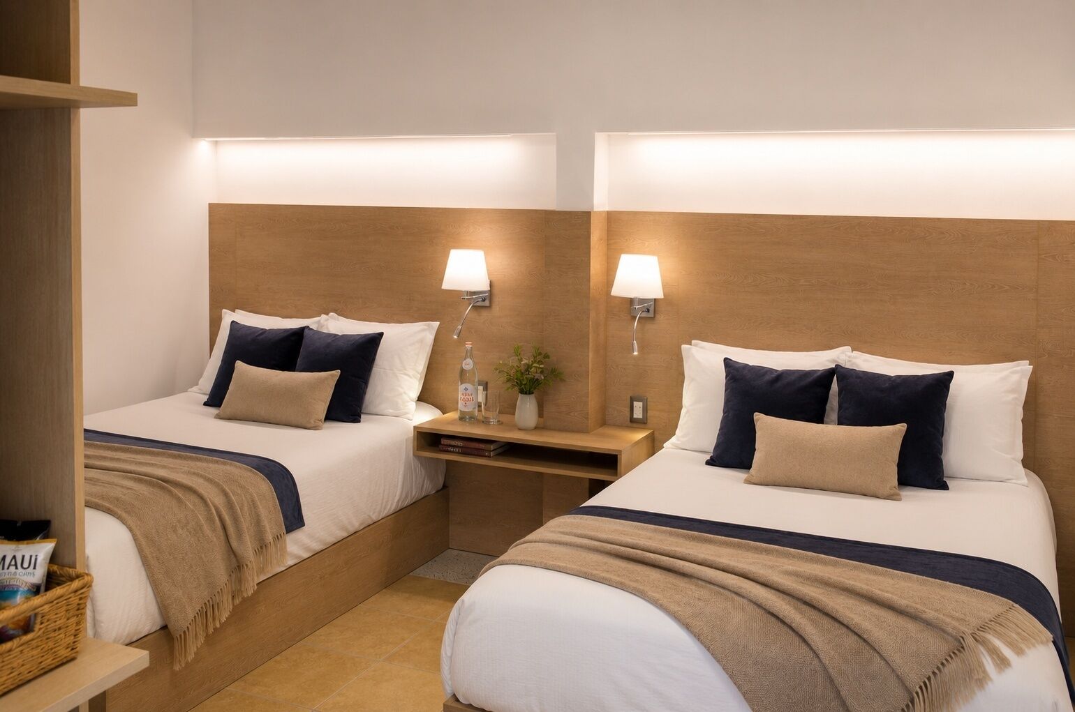 A hotel room with two beds, each with a headboard, bedside tables, lamps, and a small plant.