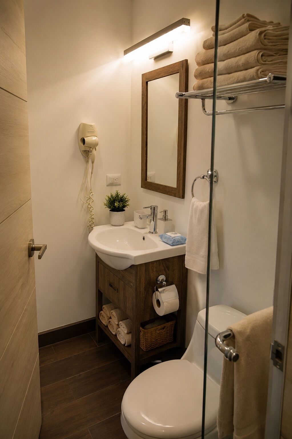 A bathroom with a sink, mirror, towel rack, toilet, and a hairdryer.