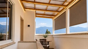 Een balkon met uitzicht op bergen, een tafel met stoelen en een bloempot.