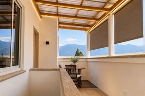 A balcony with a view of mountains, a table with chairs, and a potted plant. - Hotel Casa Bella (Antigua Guatemala)