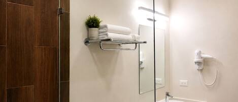 A modern bathroom with a glass shower enclosure, a white sink, a towel rack, and a hairdryer.