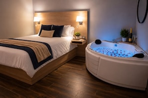 A bedroom with a large bed, a nightstand, a wall-mounted lamp, and a hot tub with rose petals.