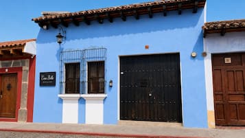 Een blauw gebouw met een zwarte deur, een raam met metalen tralies en een bord waarop staat 'Casa Bella Boutique Hotel'.