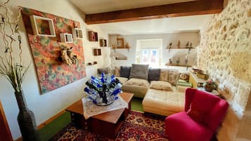 A living room with a sofa, a red armchair, a coffee table with a vase, and a patterned rug.