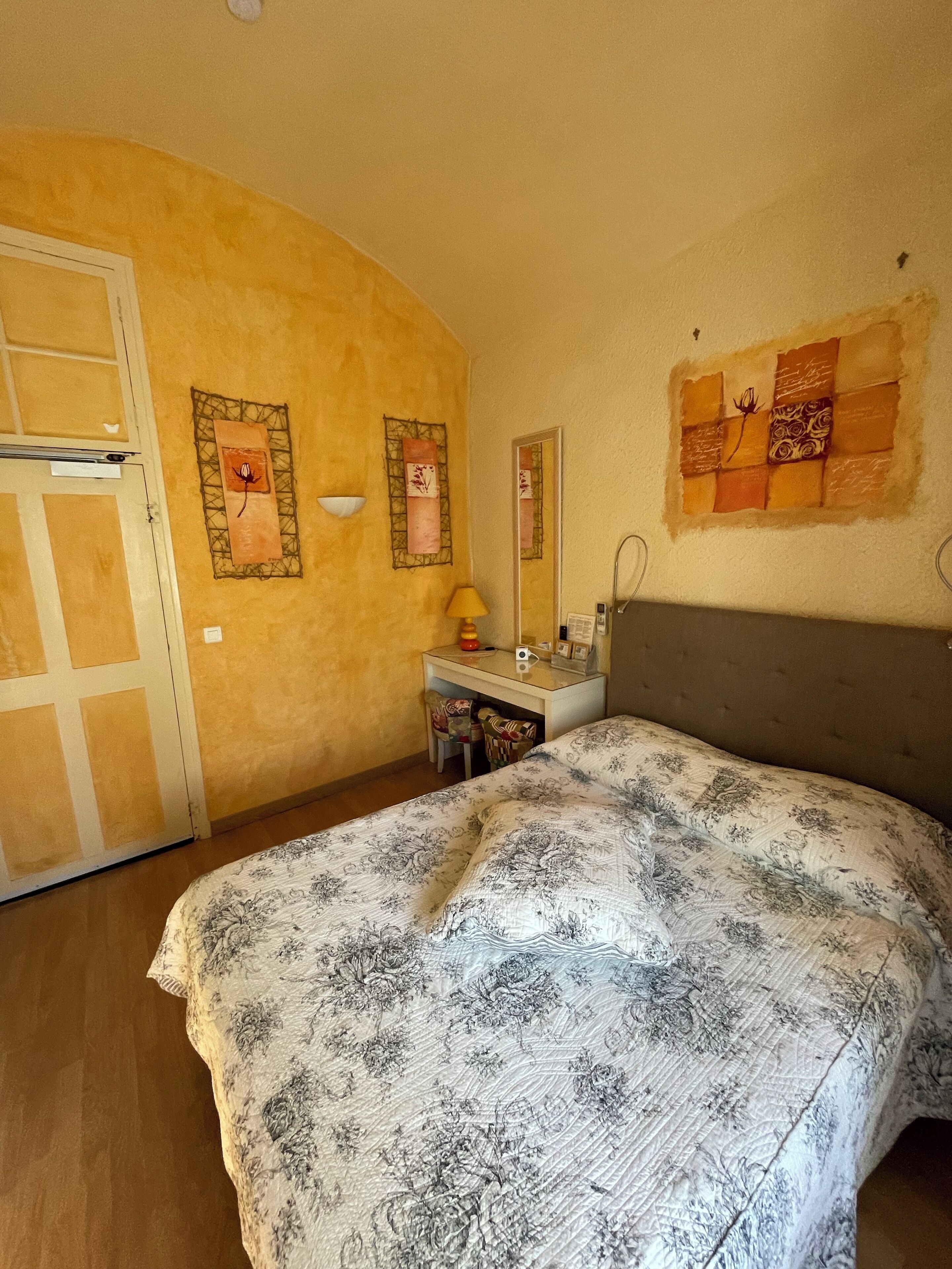 Un dormitorio con una cama, un escritorio y una silla. Hay una puerta y un espejo en la pared.