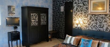A bedroom with a bed, a wardrobe, a television, and a wall with decorative patterns.