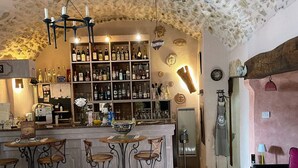 Angolo bar con soffitto in pietra, sgabelli da bar e diverse bottiglie.
