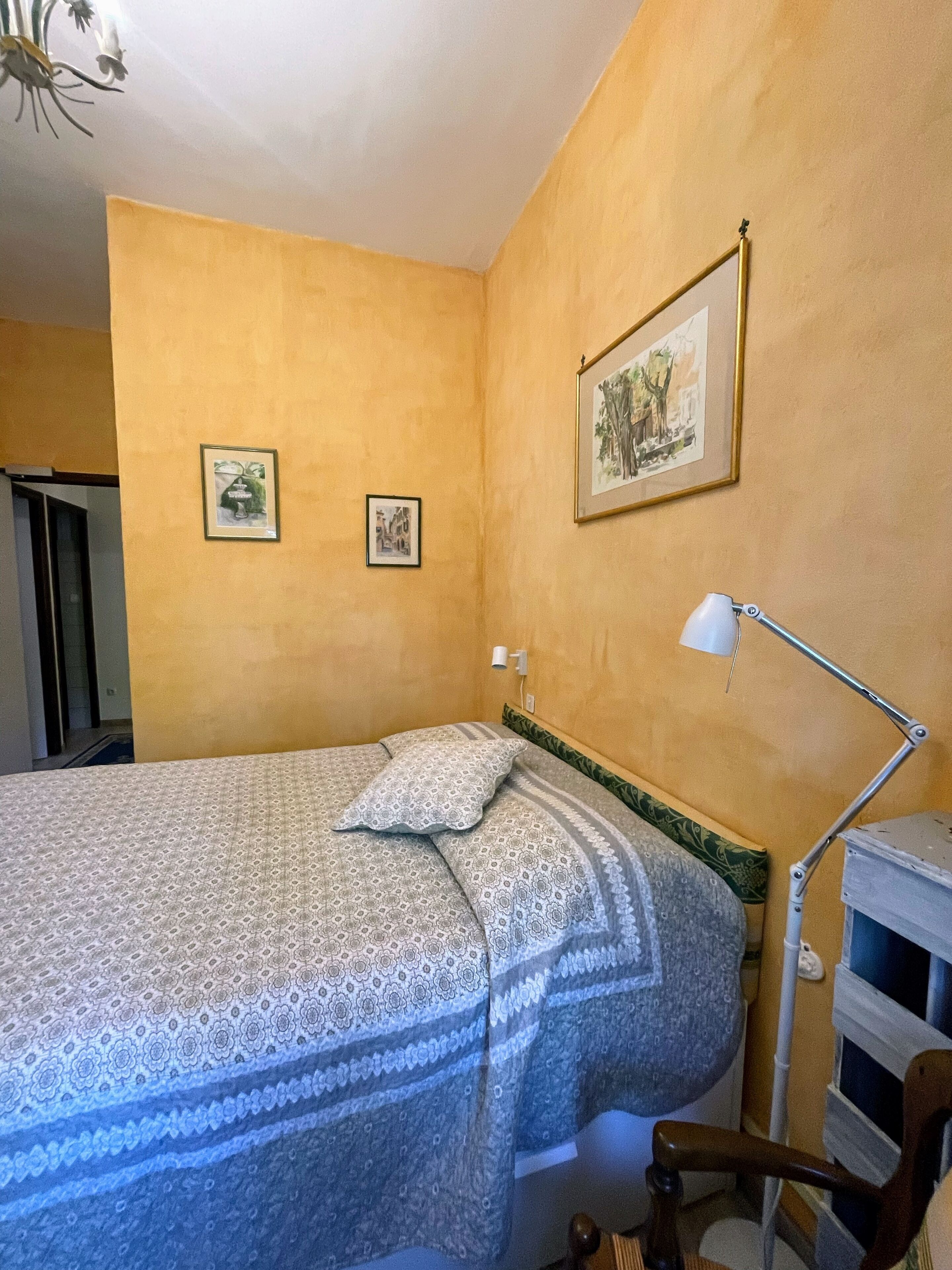 Un dormitorio con cama, escritorio, silla y dos cuadros en la pared.