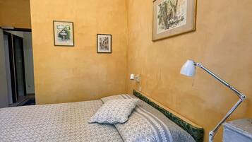 Un dormitorio con cama, escritorio, silla y dos cuadros en la pared.