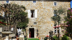 Un edificio in pietra con un ingresso centrale, piante in vaso e un piccolo giardino.