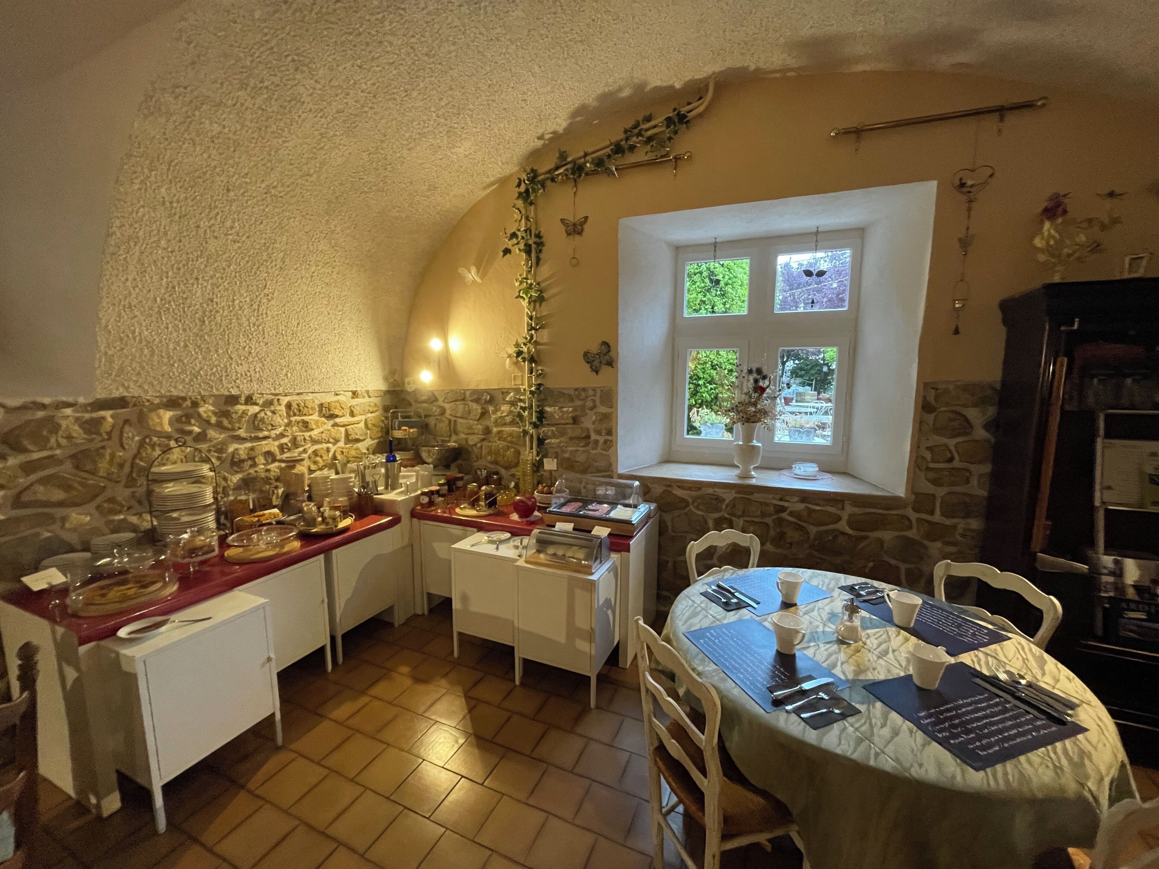 A cozy dining area with stone walls, a window with a view, and a table set for two.
