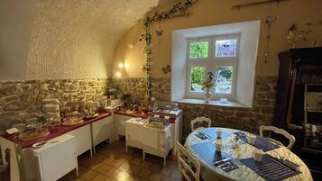 A cozy dining area with stone walls, a window with a view, and a table set for two.