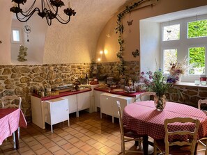 A cozy dining area with a stone wall, a chandelier, and a table set with a red tablecloth. - Hotel le Manoir du Raveyron (Vallon-Pont-d'Arc)
