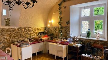 Una cocina acogedora con paredes de piedra, una araña y una ventana con vistas.