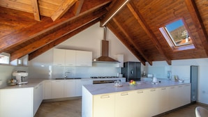 Una cucina moderna con un'isola grande, mobili bianchi e un lucernario.