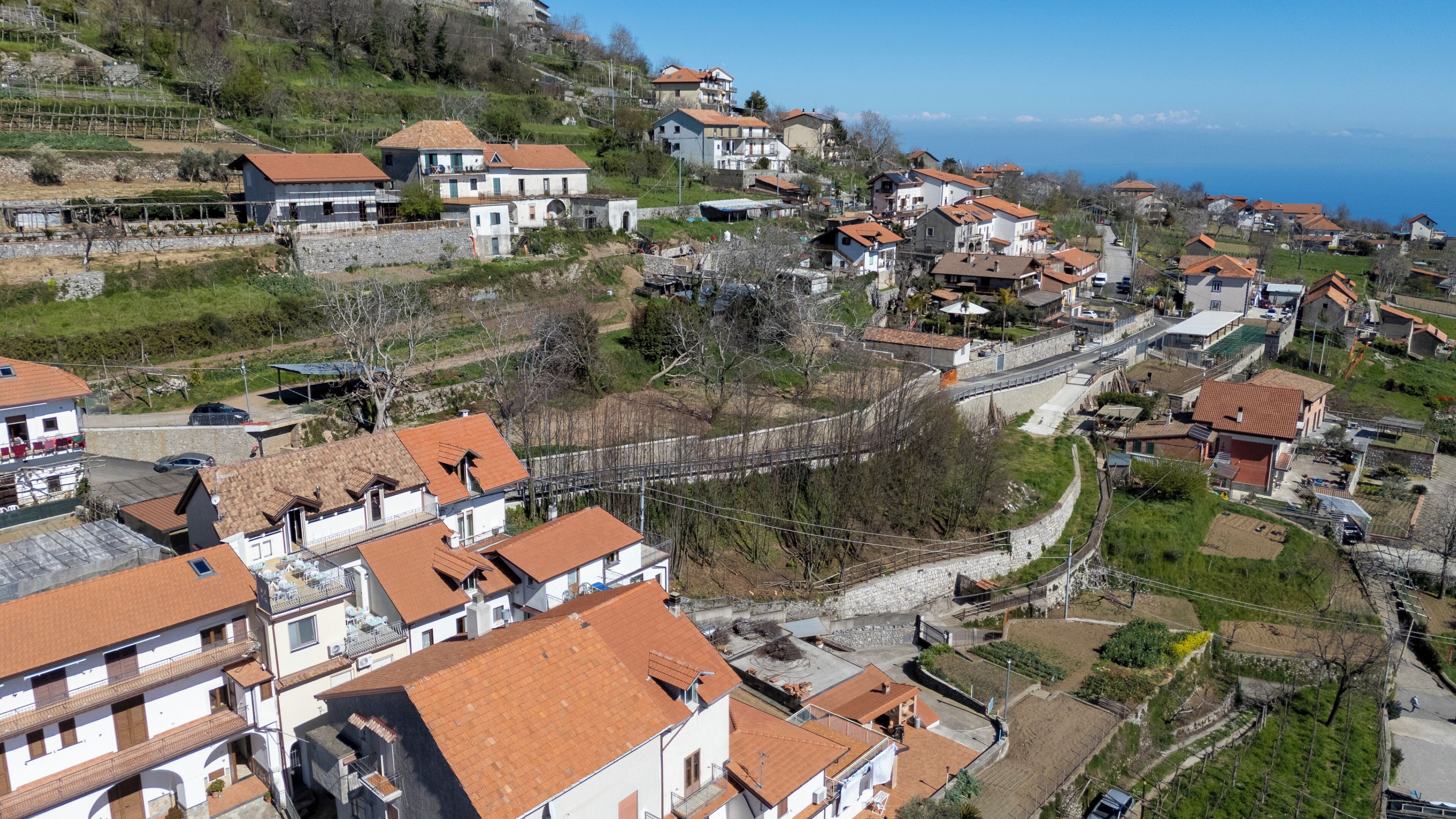 A coastal village with traditional architecture, a stone bridge, and terraced vineyards.