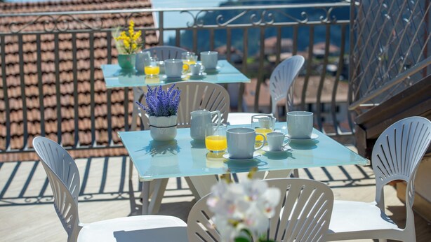 Una terrazza con un tavolo apparecchiato per la colazione, sedie e vista sul paesaggio.
