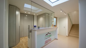 Una moderna area reception con pareti divisorie in vetro, una scrivania reception, una scala e un lucernario.