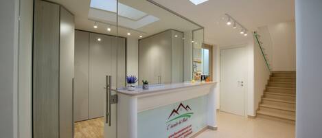 Et moderne receptionsområde med glasvæg, receptionistskranke, trappe og ovenlys.