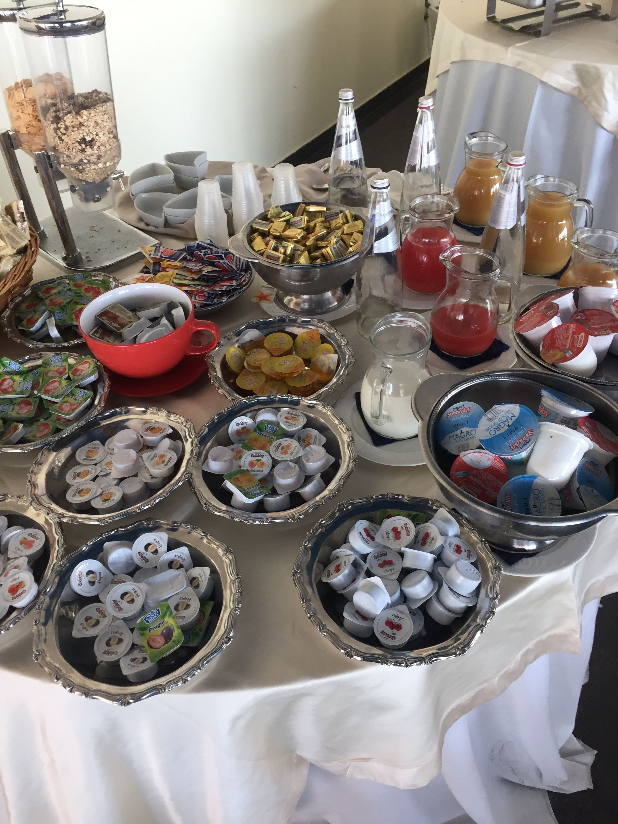 Een buffet met diverse gerechten en drankjes, zoals yoghurt, snacks en frisdranken.