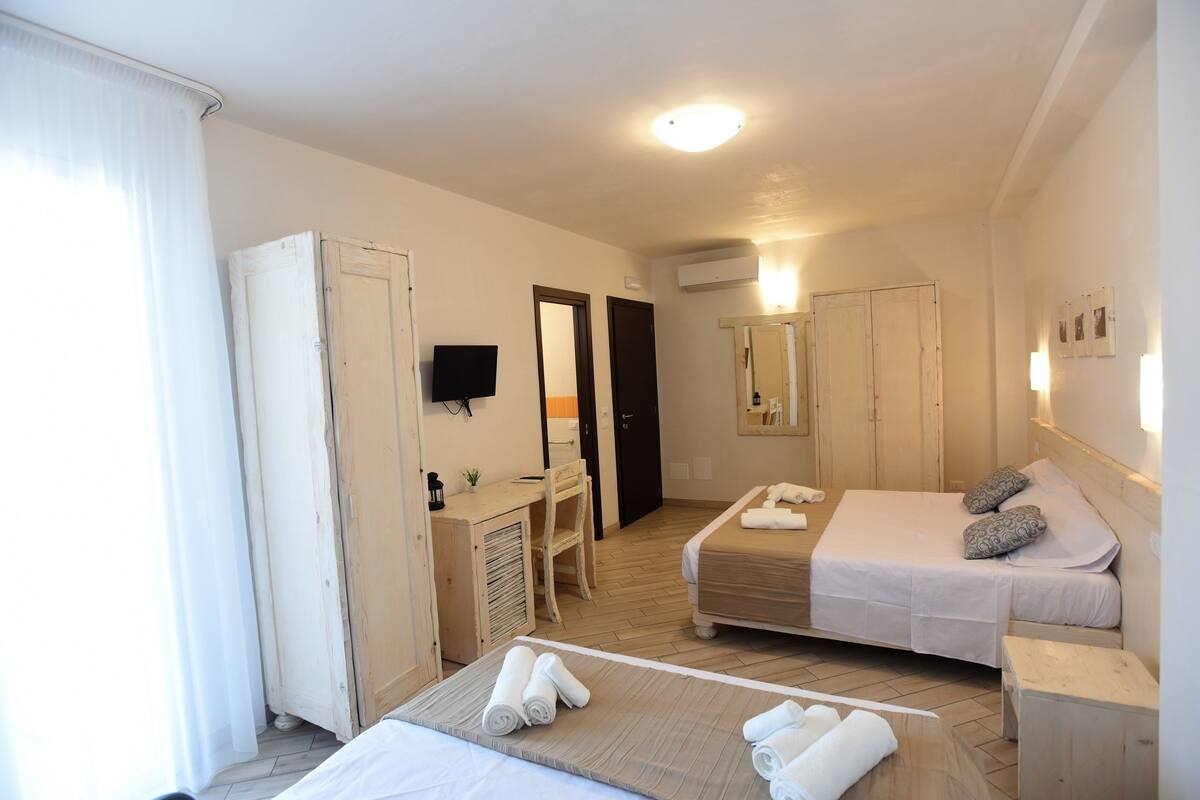 Una camera d'albergo con due letti, una scrivania, una sedia e un armadio.