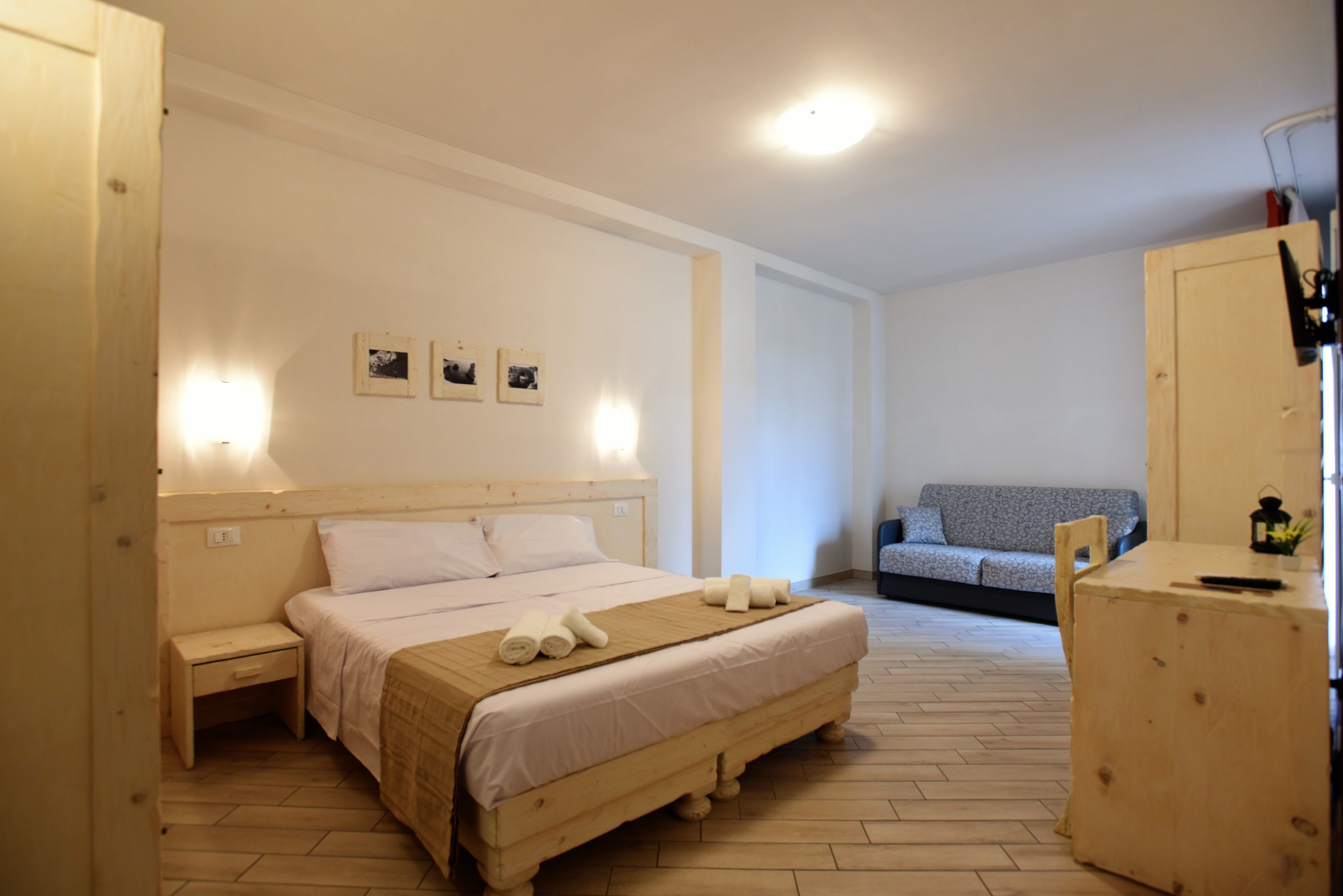 Ein Schlafzimmer mit einem hölzernen Bett, Nachttischen, einem Sofa und einem kleinen Tisch mit einer Laterne.