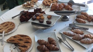 Une table de buffet proposant une variété de pâtisseries et de desserts, notamment des tartes, des croissants et des brownies.