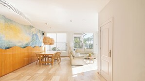 Een ruime woonkamer met een houten accentmuur, een eethoek, een bank en uitzicht op de omgeving.
