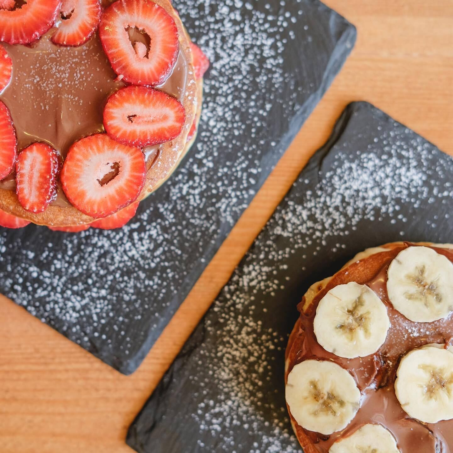 Postre con fresas y plátanos en un plato, espolvoreado con azúcar glass.