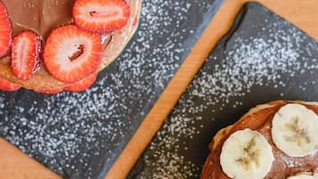 Postre con fresas y plátanos en un plato, espolvoreado con azúcar glass.