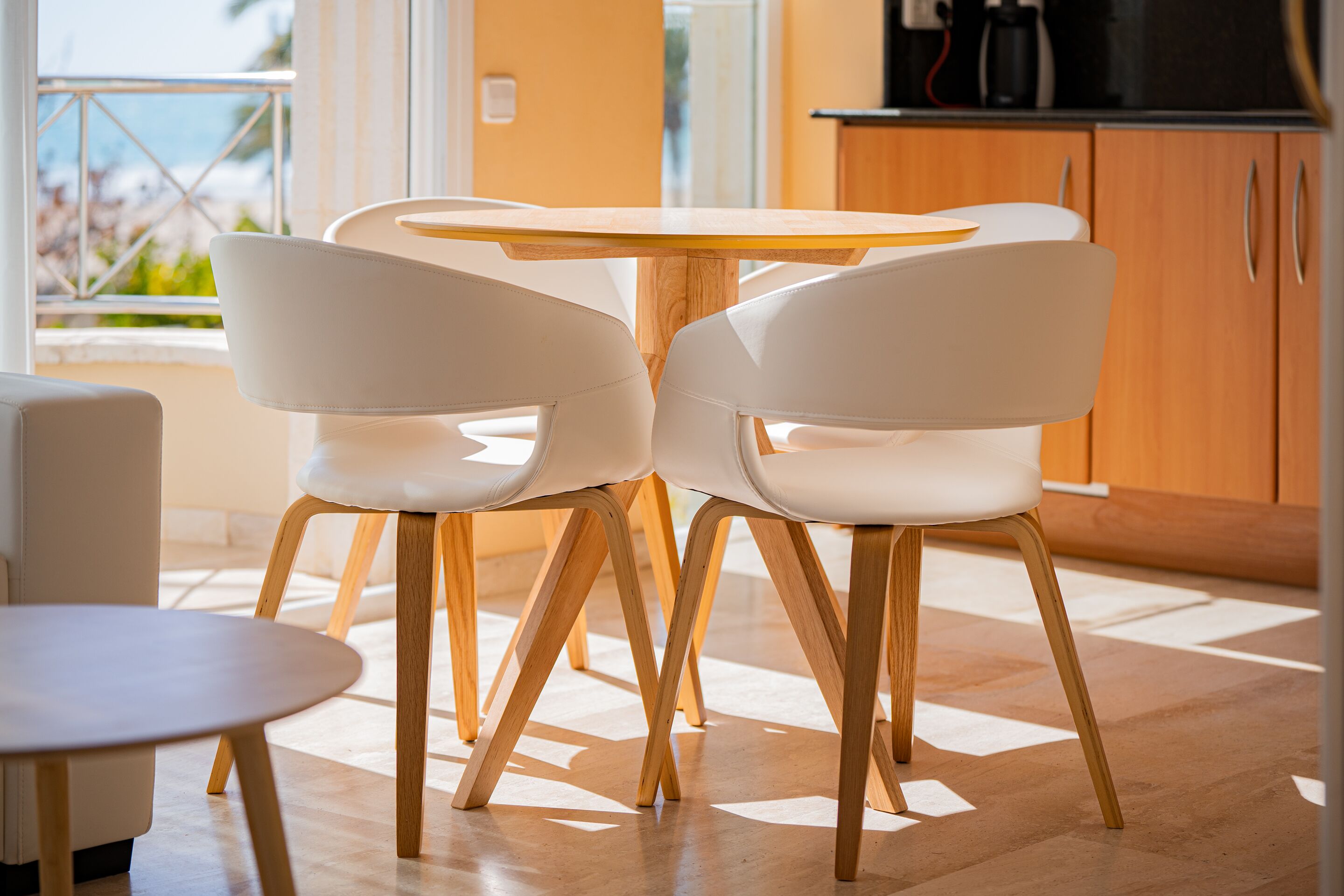 Un comedor moderno con una mesa redonda y dos sillas blancas de patas de madera.